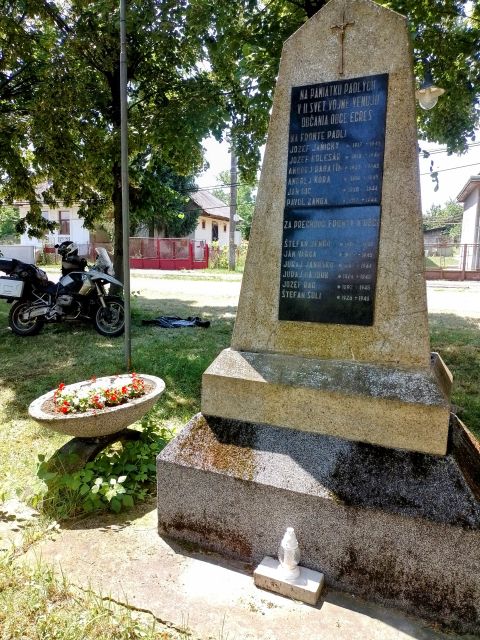 Ich mache eine Pause unter schattigen Bumen, neben einem Denkmal fr die Gefallenen des Zweiten Weltkriegs.